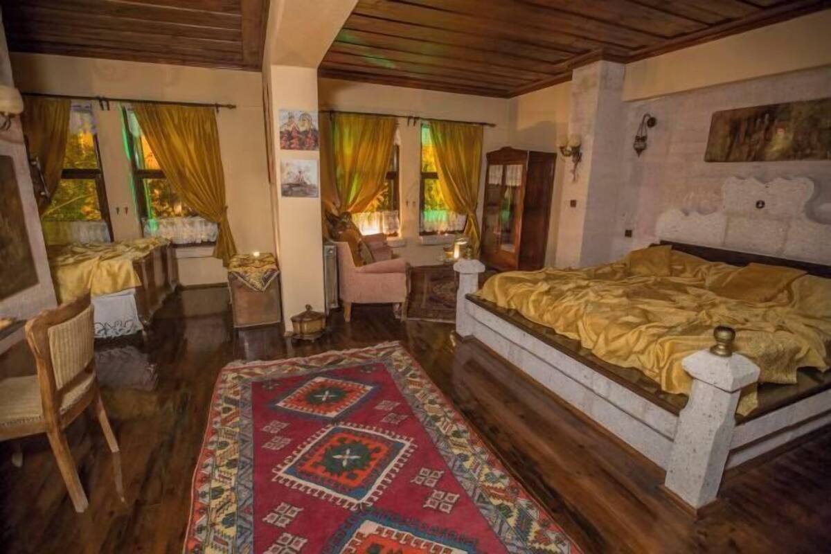Una habitación tradicional con cama, una silla, una mesa y un tapete estampado.