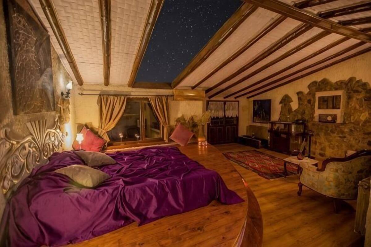 Un dormitorio con cama, sofá, chimenea y vistas al cielo nocturno.