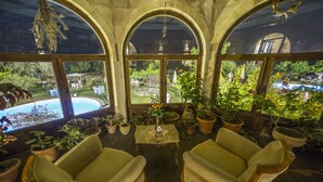 Une véranda dotée de fenêtres en arc de cercle, une piscine et diverses plantes en pot.