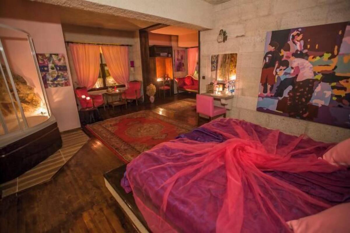 Una habitación con cama, escritorio, sillas y un cuadro en la pared.