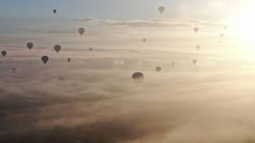 Globos aerostáticos flotando sobre un paisaje con cielo iluminado por el sol.