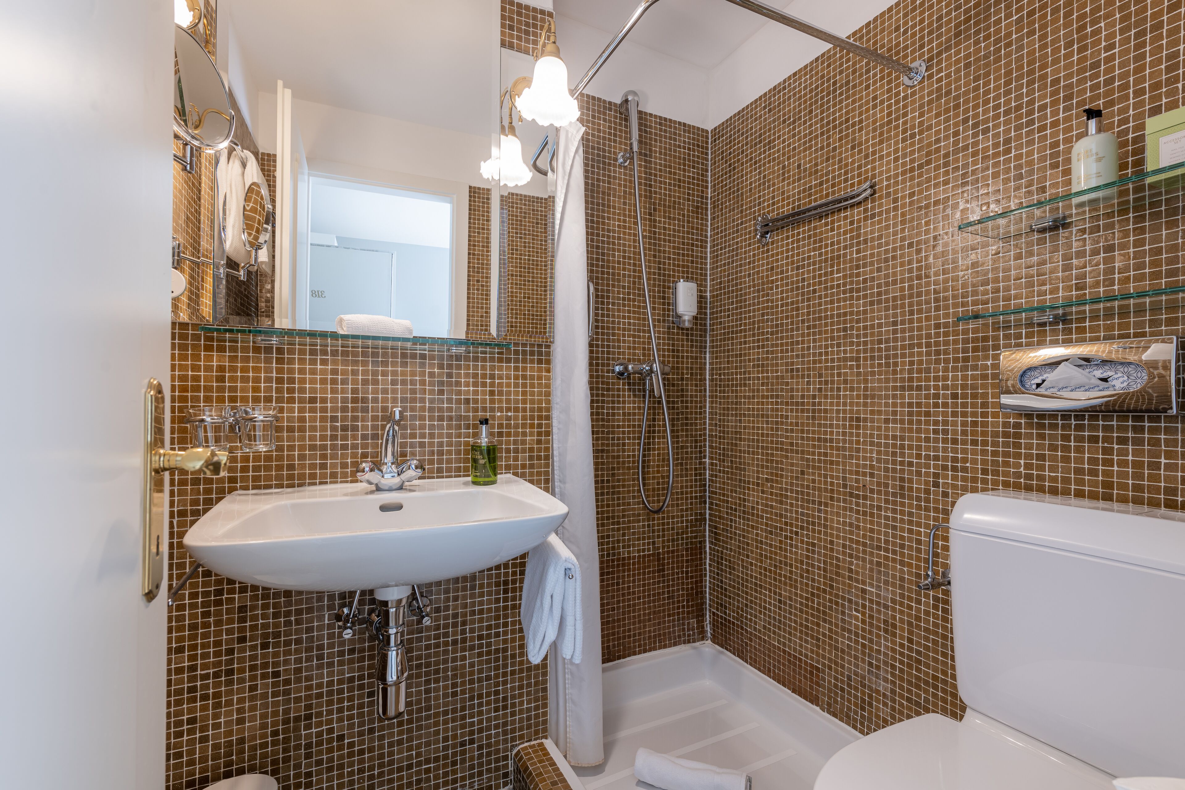 A bathroom with a white sink, a glass shower enclosure, and a toilet.