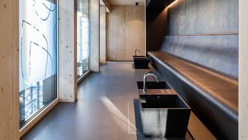 A modern bathroom with a wooden floor, a black sink, and a bench.