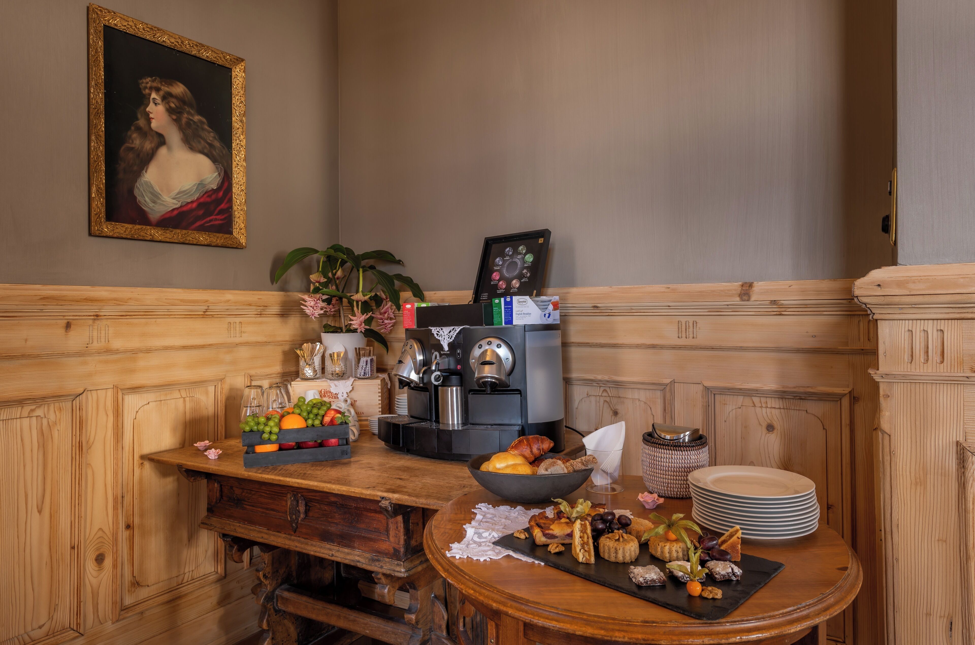 A wooden bench with a table beside it, a coffee machine, and a framed picture on the wall.