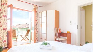 A bedroom with a bed, a desk, a chair, and a view of the outside. - Villa Mare (Hvar)