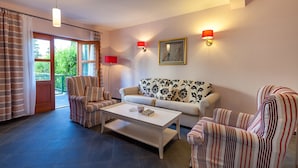 A living room with striped armchairs, a white sofa, a coffee table, and two wall-mounted lamps. - Villa Dane (Hvar)