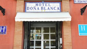 The entrance to Hotel Dona Blanca, featuring a large glass door, a white awning, and a balcony with ornate metal railings. - Hotel Doña Blanca (Seville)