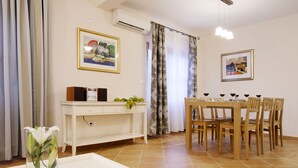 A dining area with a table set for six, a white console table with a plant, and two framed artworks on the walls. - Villa Cvita (Hvar)