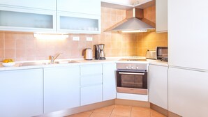 A modern kitchen with white cabinets, a Bosch oven, a sink, and a coffee maker. - Villa Cvita (Hvar)