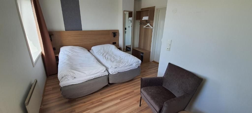 Une pièce comprenant un lit, une chaise et une armoire.