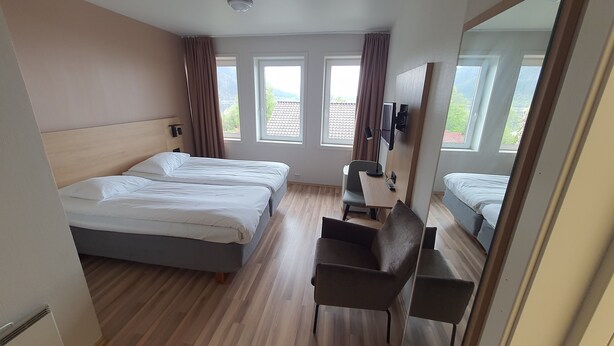 A hotel room with two beds, a desk with a chair, and a large mirror. - Systra Hotel Søvik (Ålesund)