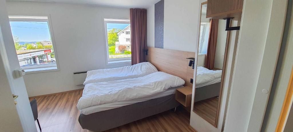 A bedroom with a bed, a nightstand, a mirror, and a window.