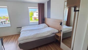 A bedroom with a bed, a nightstand, a mirror, and a window.