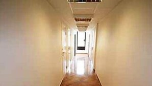 A long, narrow hallway with a tiled floor and plain walls. - Systra Hotel Søvik (Ålesund)