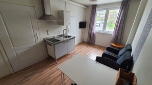 A compact kitchen with a sink, stove, and cabinets, a small dining table, and a sofa. - Systra Hotel Søvik (Ålesund)