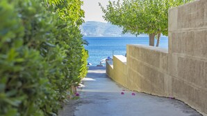 Un sendero que lleva a una playa, con vista al mar y una montaña al fondo.