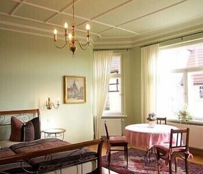 A room with a bed, a round table, and a chandelier.