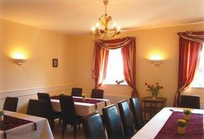 A dining area with tables and chairs, a chandelier, and curtains.