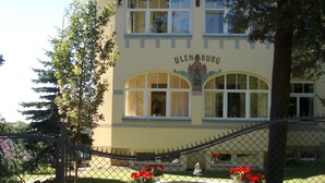 A building with the name "ULENBURG" on the facade, featuring multiple windows and a balcony.
