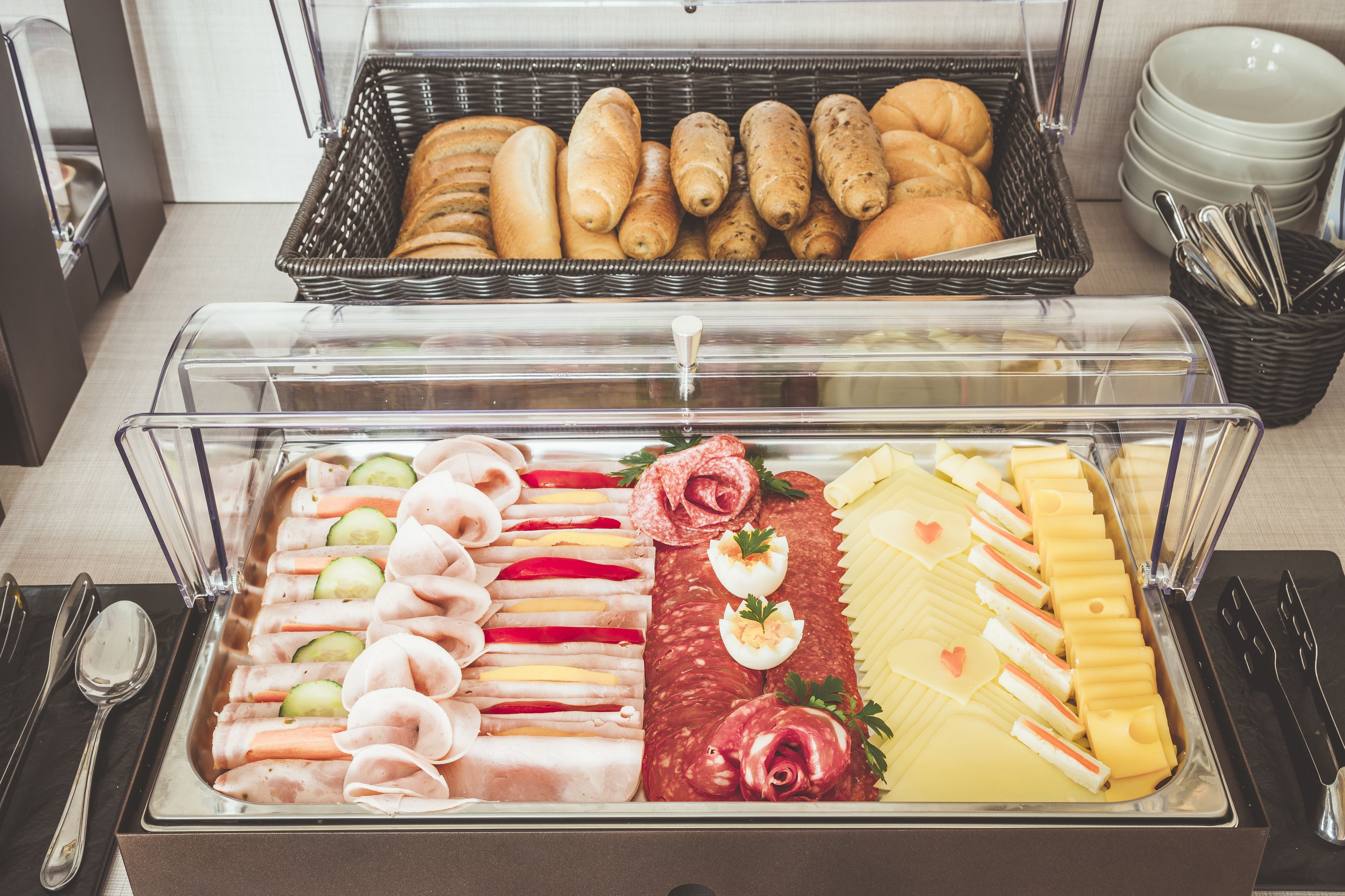 A buffet with various food items including meats, cheeses, and pastries.