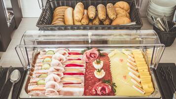 A buffet with various food items including meats, cheeses, and pastries.