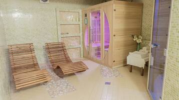 A sauna room with wooden benches, a glass-enclosed shower area, and a tiled floor.