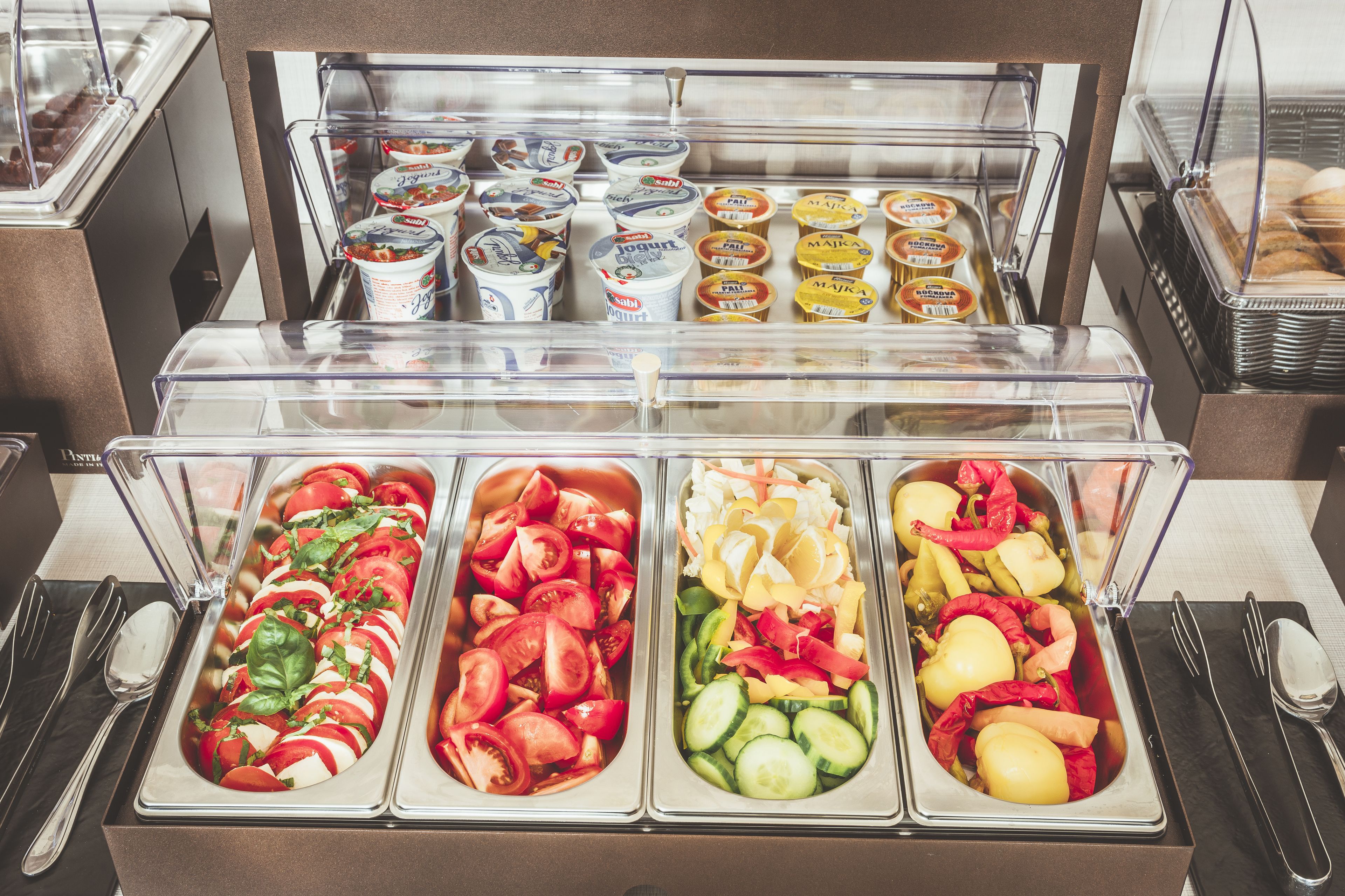 A buffet with various food items including yogurt, salads, and vegetables.