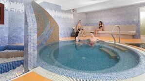 Una piscina interior con paredes de azulejos y escalones que bajan al agua.