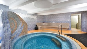 Una piscina interior moderna con paredes de mosaicos y agua de color azul transparente.