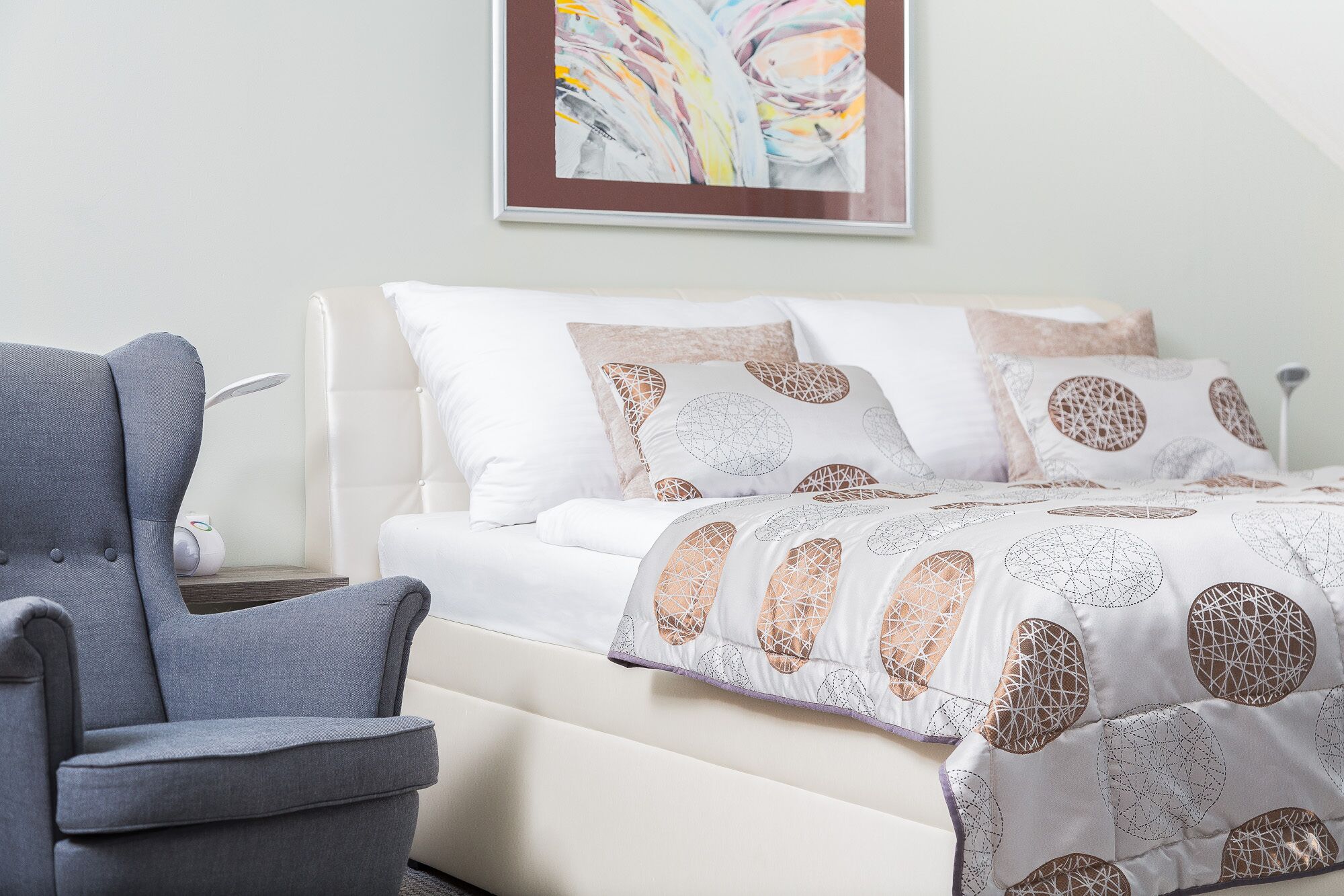 Un dormitorio ordenado con cama, almohadas y una silla.