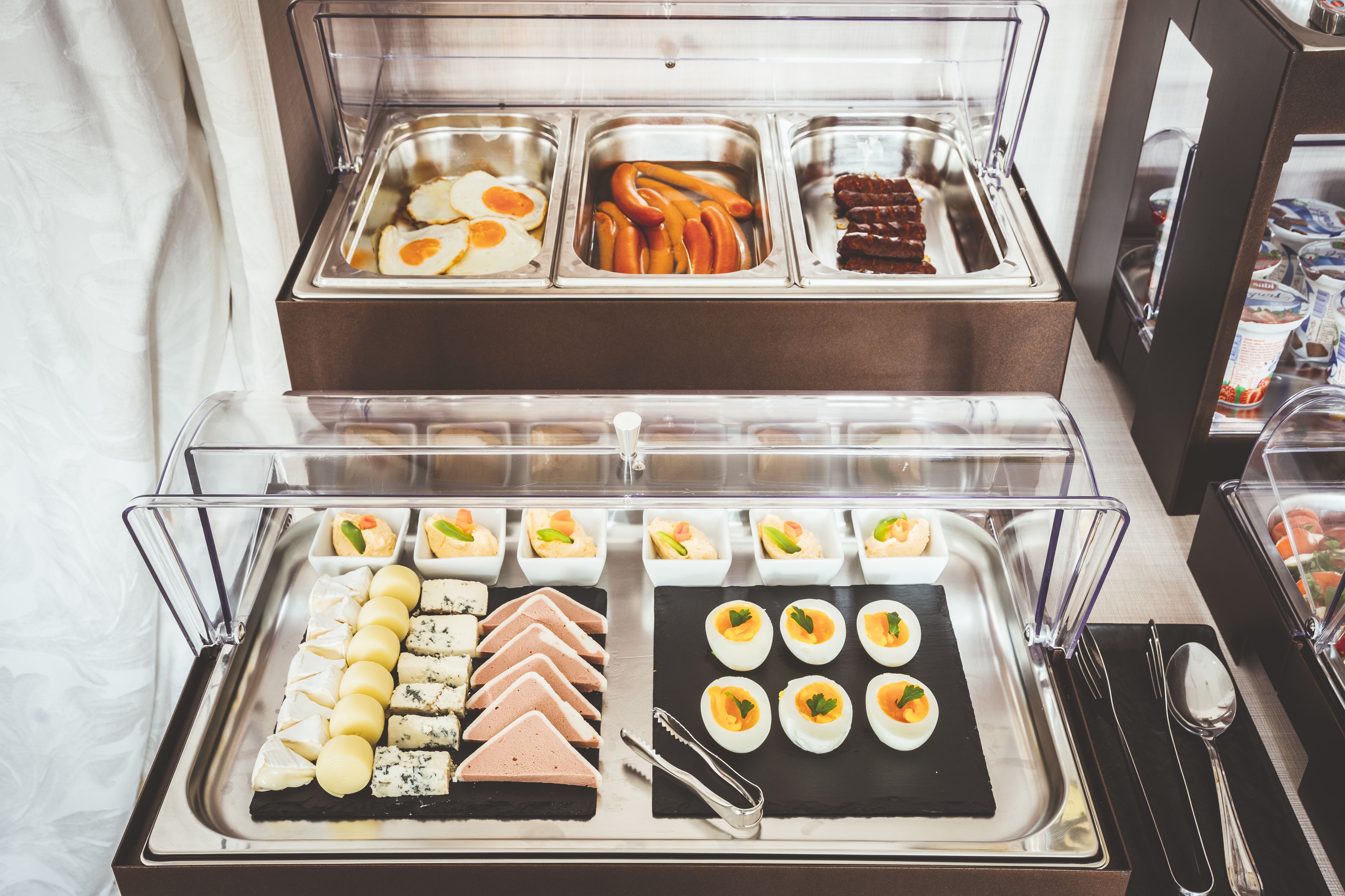A buffet with various food items including eggs, sausages, and cheese.