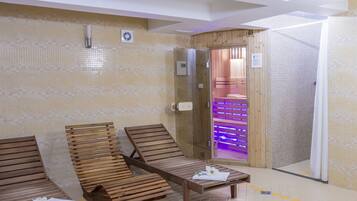 A spa area with wooden loungers, a massage table, and a shower area with a tiled wall and a glass door.