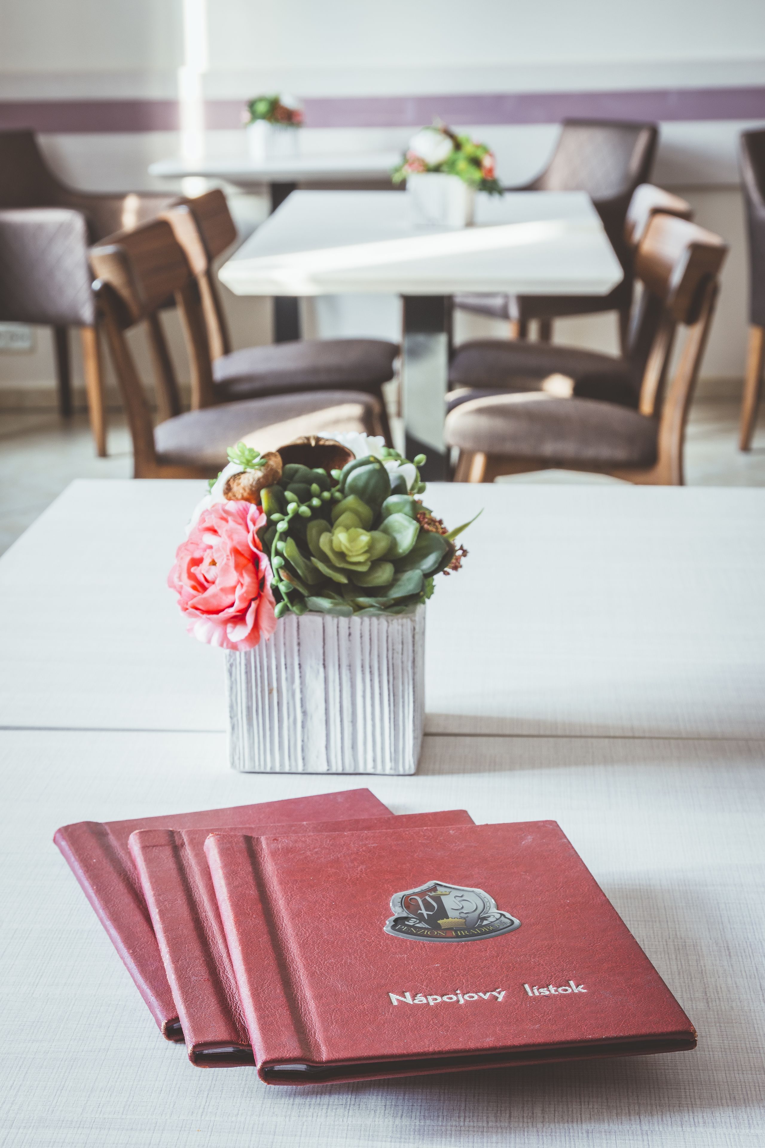 Uma mesa de jantar com um vaso de flores e uma pilha de cadernos vermelhos.