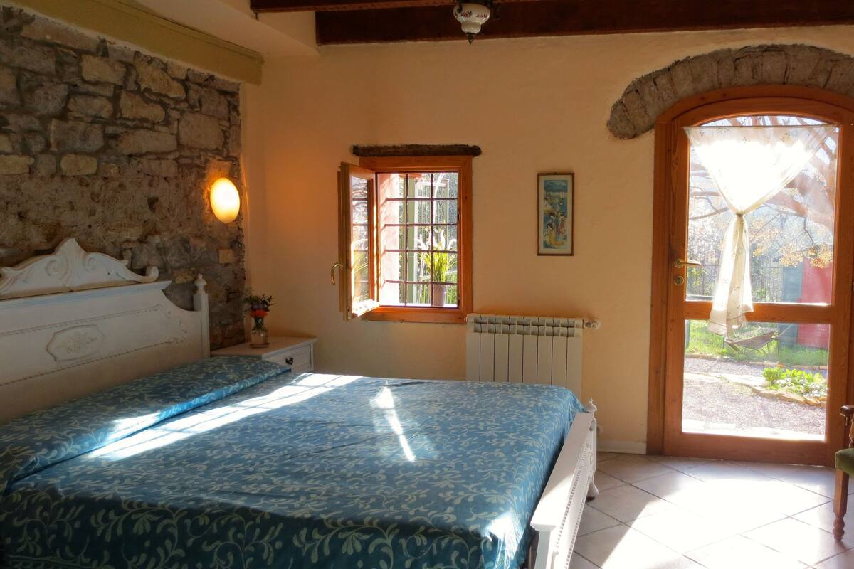 Une chambre à coucher avec un lit, une fenêtre, un radiateur et une porte donnant sur l’extérieur.