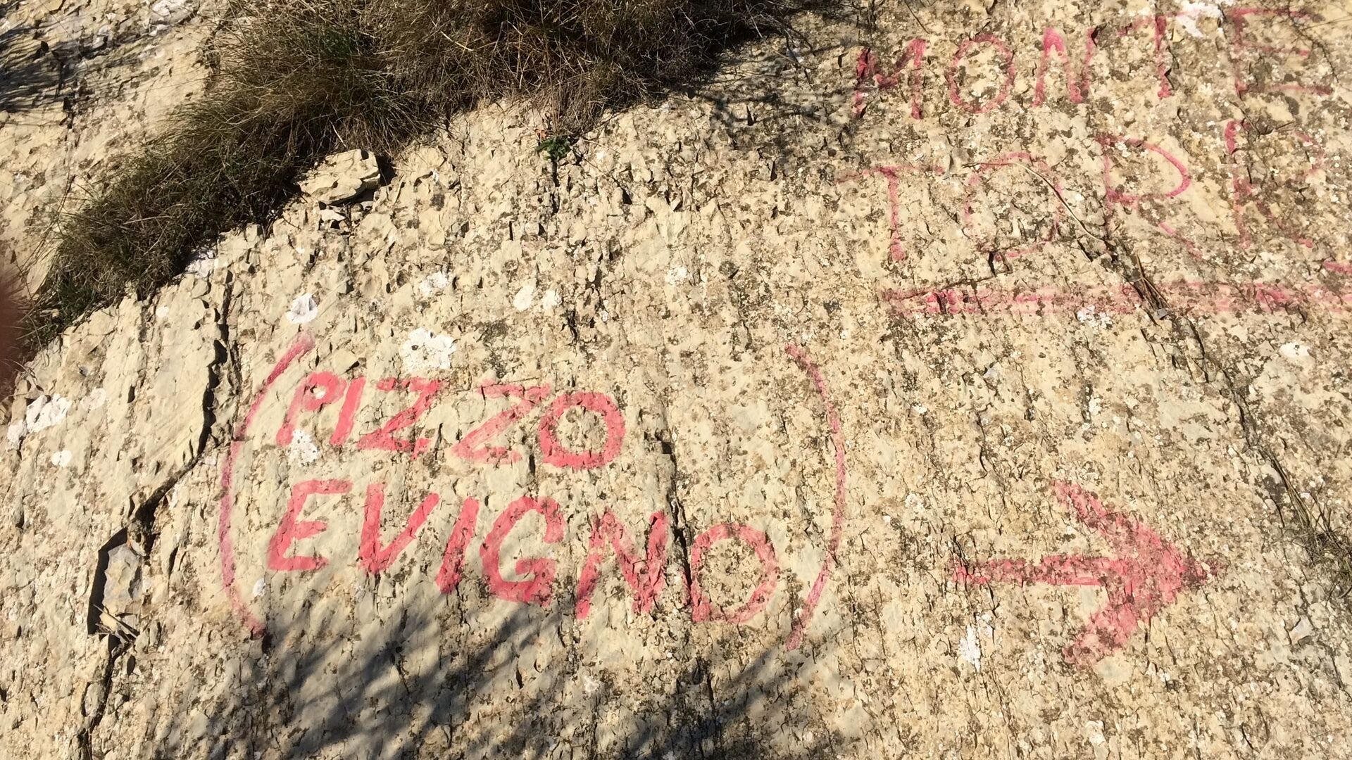 Ein Felsen mit roter Graffiti-Beschriftung und Pfeilen.