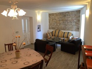 A living room with a dining table, sofas, and a stone wall.
