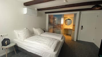 A bedroom with a bed, bedside table, and a round mirror.