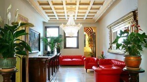 Un vestíbulo amplio con techo alto, un sofá rojo y plantas en macetas.