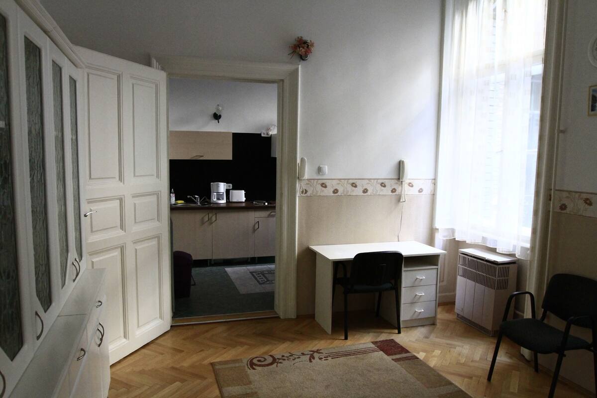 A compact kitchen with a dining area, a white desk, and a chair.