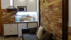 A compact living space with a kitchenette, a sofa, and a patterned floor. - RingAvenue Apartments (Budapest)