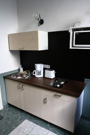 A compact kitchen with a sink, coffee maker, toaster, and a microwave.