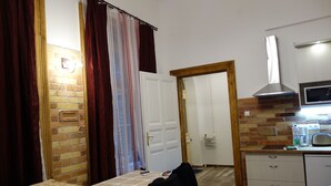 A compact hotel room with a bed, a small kitchenette, a microwave, and a brick wall. - RingAvenue Apartments (Budapest)