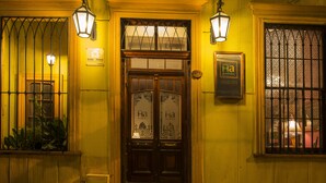 Entrada de un hotel con un par de puertas de madera dobles, dos faroles en la pared y un letrero que indica el nombre 'Solar home'.