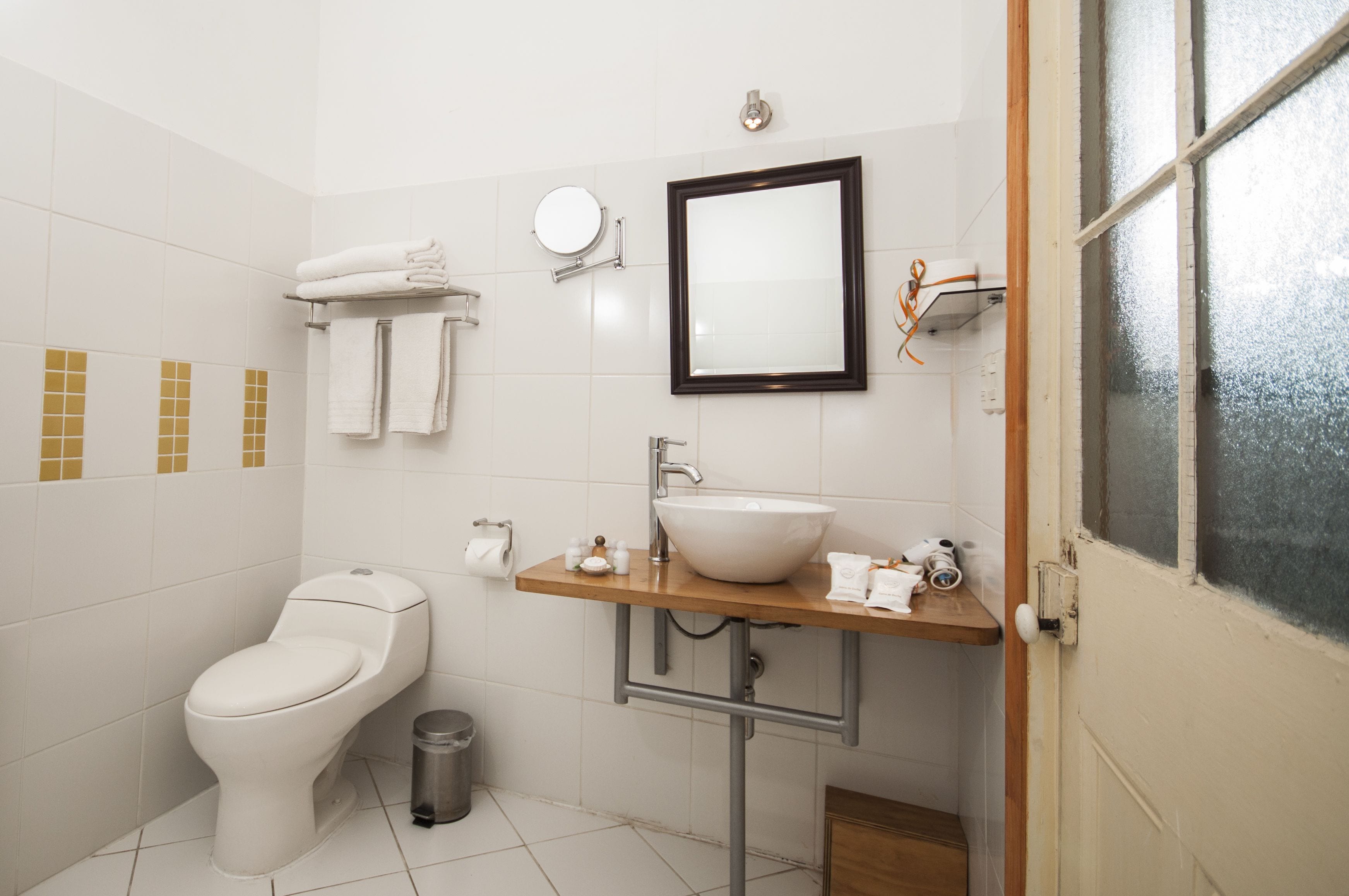 Casa de banho com sanita, lavatório, espelho e porta-toalhas.