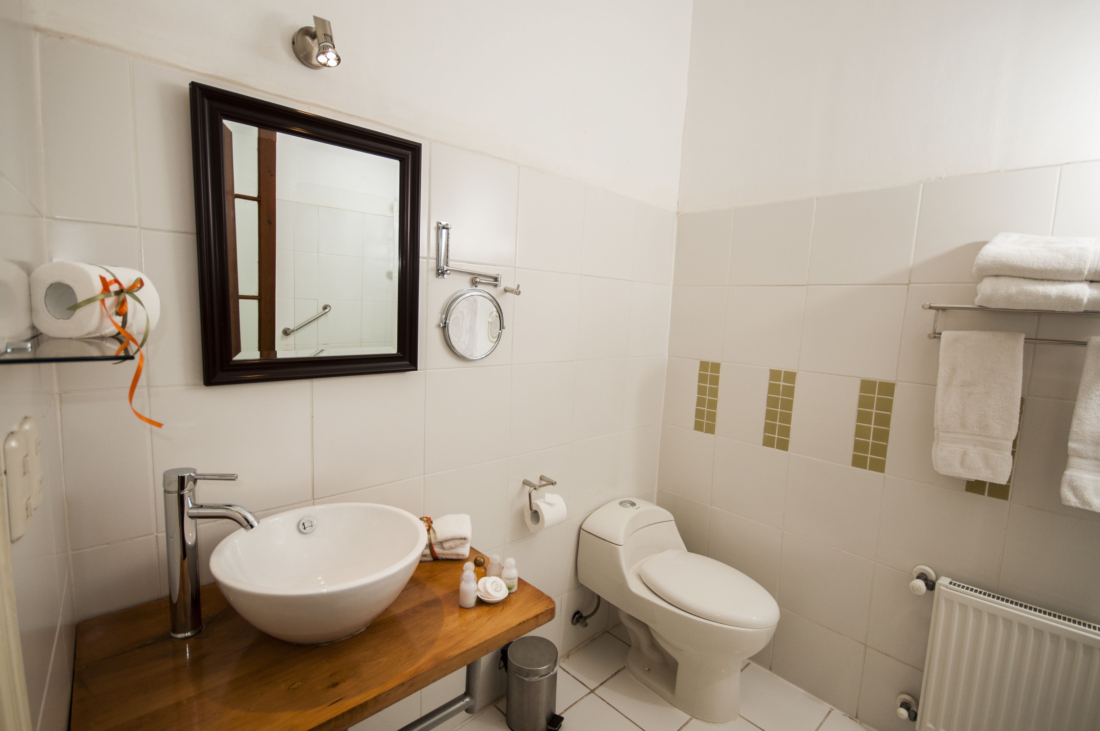 Un baño moderno con tocador de madera, un lavamanos grande, inodoro y espejo.