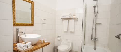 A modern bathroom with a large white sink, a freestanding toilet, a bathtub, and a shower.