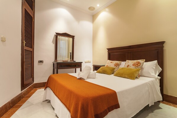 A hotel room with a large bed, a wooden headboard, a nightstand, and a mirror.