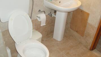 Un baño con inodoro, lavabo y ducha.