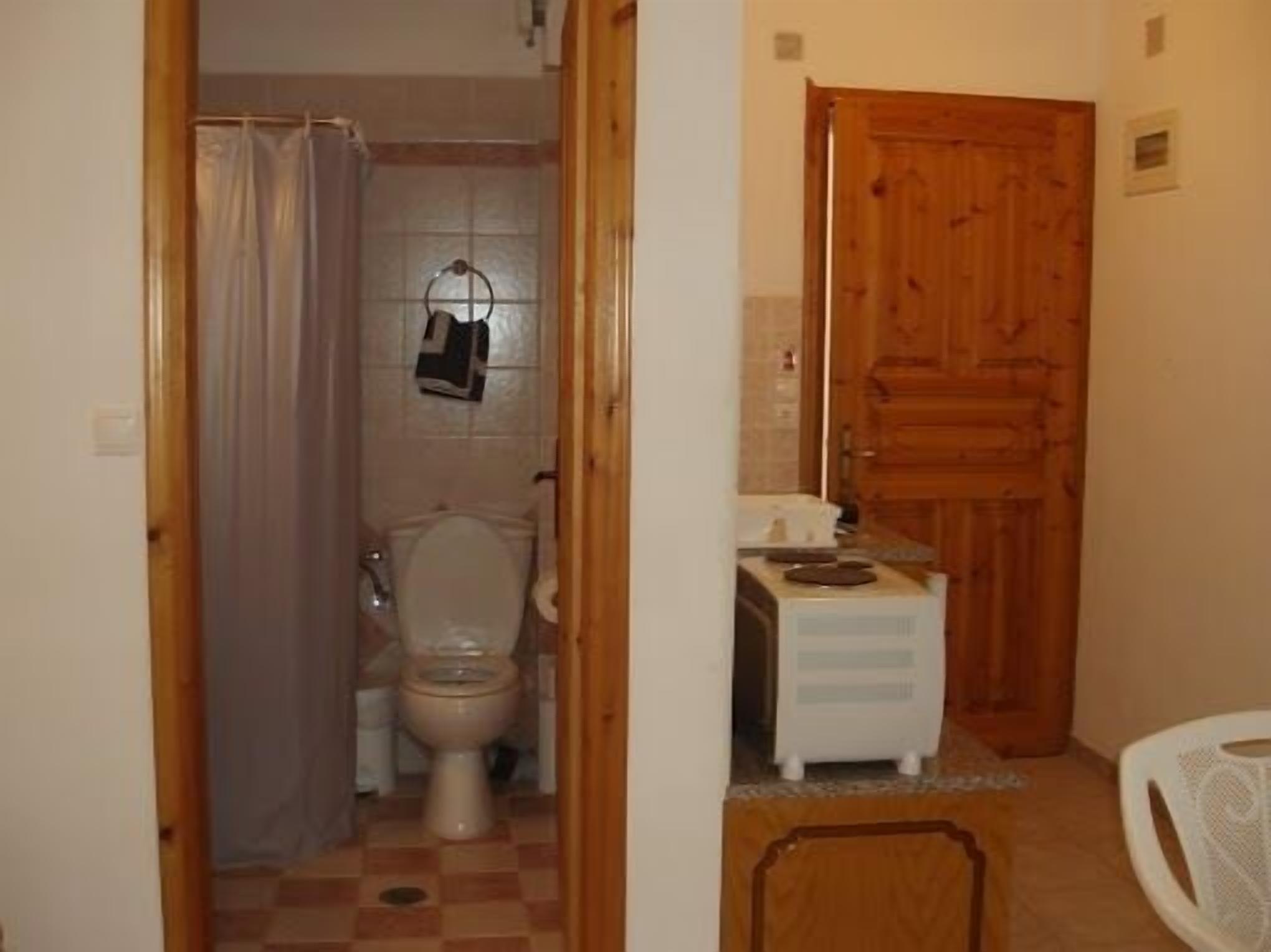 Un baño pequeño con inodoro, lavabo y puerta de madera.