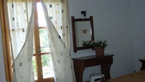 A room with a wooden desk, a small stool, a mirror, and a potted plant. - Hellen Studios (Skiathos)